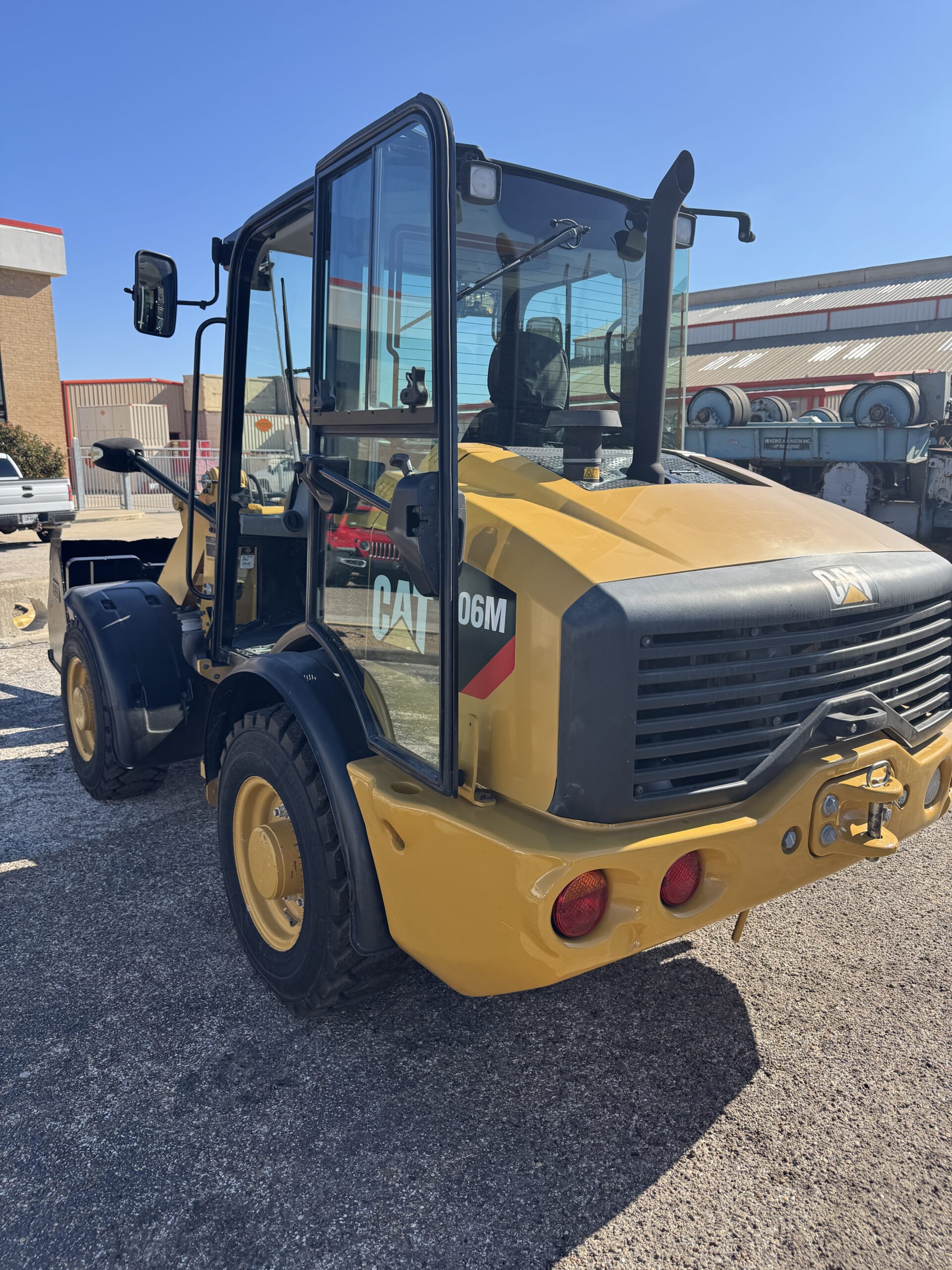 Left rear side view of compact Cat 906M loader with bucket
